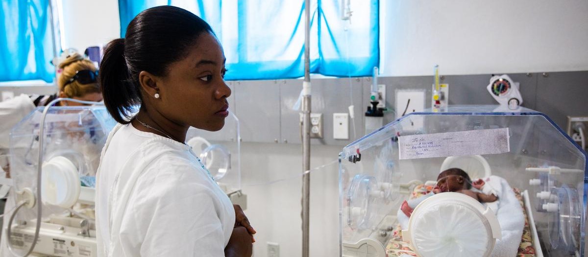 A nurse in a neonatal intensive care unit checks a reading