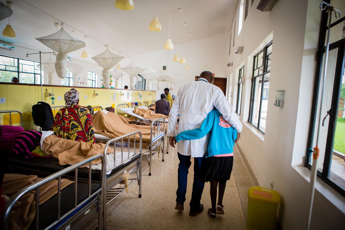 Dr. Cyprien Shyirambere walks with Blandine Umurisa, 12, who is undergoing chemotherapy treatment for T-cell acute lymphoma at Butaro District Hospital.