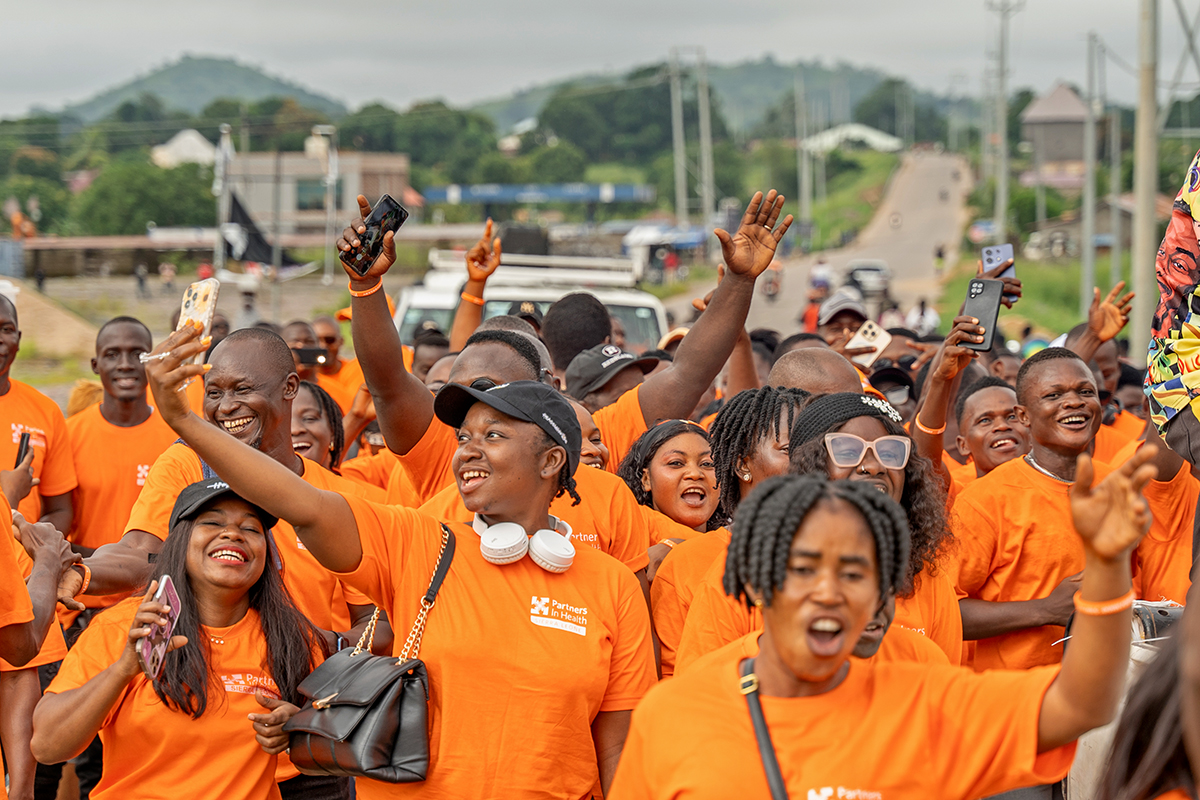 PIH staff march through Kono in orange shirts. Photo by Chiara Herold / PIH