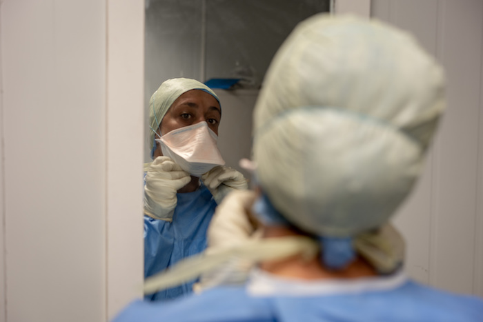 Caregiver adjusting her mask at the mirror 