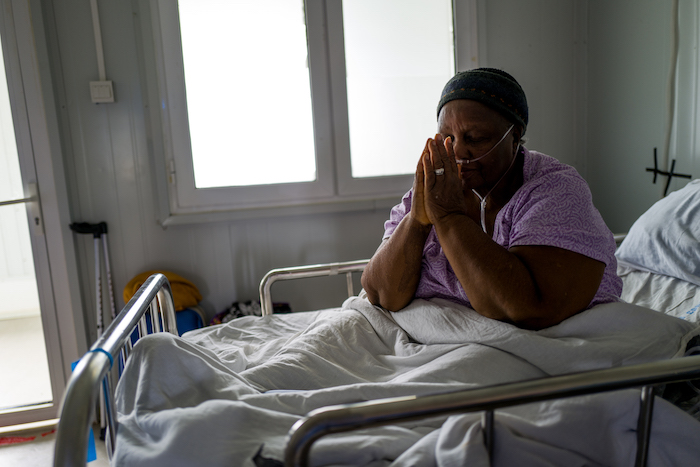 Patient praying with oxygen container hooked on