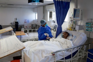 patient laying in hospital bed with clinician at bedside