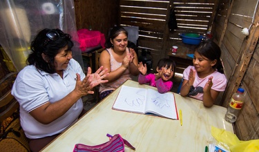 Community health worker Inela Espinoza teaches educational games to a family in their home.