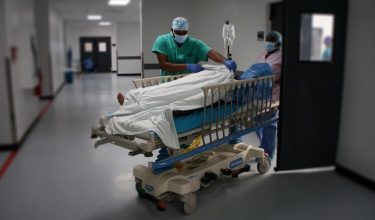 Dr. Christophe Milien wheels a patient into a room after surgery at University Hospital in Mirebalais, Haiti,