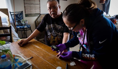 A community health worker in Navajo Nation checks a patient's blood sugar.
