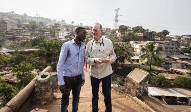 Paul Farmer stands on the Tengeh Town Bridge with Ibrahim Kamara in Freetown, Sierra Leone in 2015.