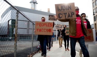 Protesters carry signs in support of the People's Vaccine in Cambridge, Massachusetts.