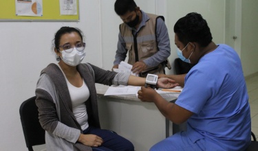 A staff member gets her blood pressure taken before receiving the vaccine for COVID-19.