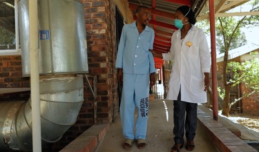 A PIH nurse and TB patient walk outside at Botsabelo Hospital 