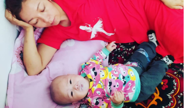 Maral Shorayeva laying down with her infant daughter