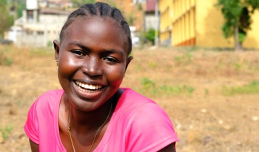 Saffiatu Sesay received care for tuberculosis at Lakka Government Hospital in Sierra Leone. She smiles for the camera and wears a pink shirt.
