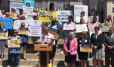 advocates gather outside the Boston Statehouse to support funding local health systems