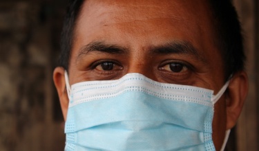 Mental health patient Gábriel (name changed) stares into the camera, while wearing a surgical mask.
