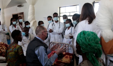 Dr. Paul Farmer teaches students from the University of Global Health Equity at a patient's bedside at Butaro District Hospital.