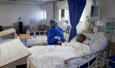 patient laying in hospital bed with clinician at bedside