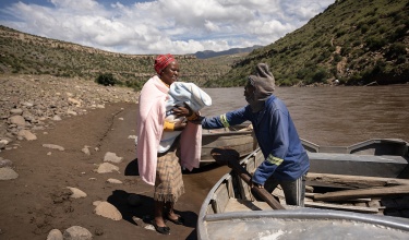 In Lesotho, ‘Masebabatso Mokatlela and her day-old newborn are helped into a canoe that will bring them across the river to their home village.