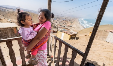 A mother holds her toddler on her front porch in rural Peru