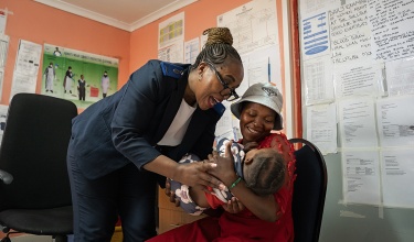 Nurse hands newborn to mother
